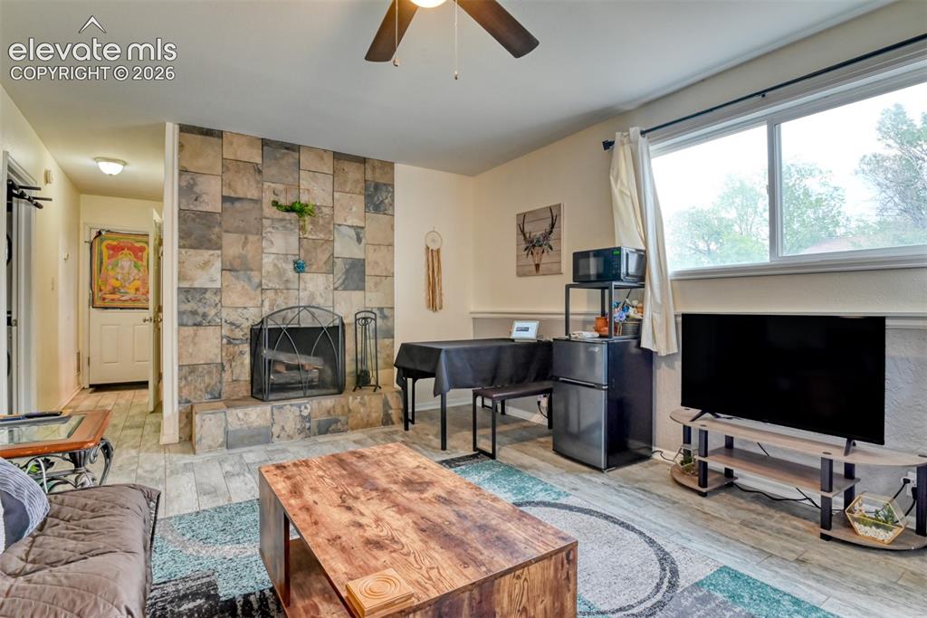 Image 27 of 46: Living area featuring a stone-clad fireplace with a metal screen, wood-fini