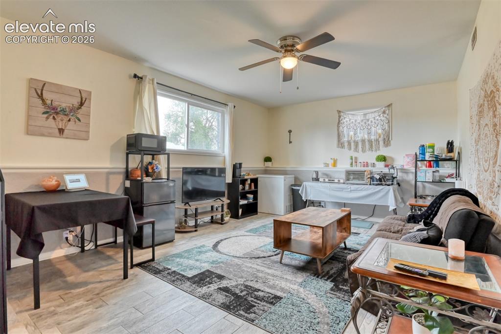 Image 28 of 46: Spacious room featuring wood-finish flooring, a ceiling fan, and abundant n