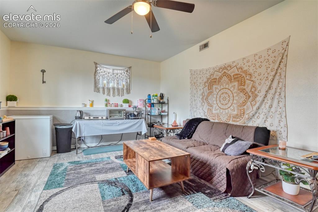 Image 29 of 46: Wood-finish flooring with a ceiling fan overhead