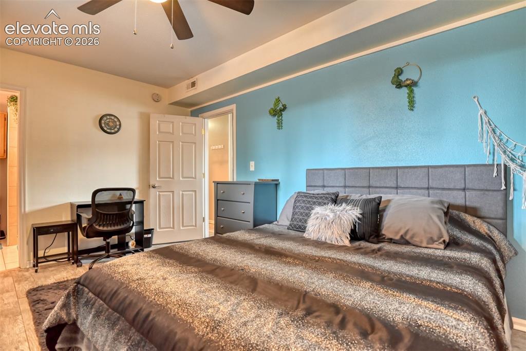 Image 30 of 46: Bedroom featuring a paddle ceiling fan, white paneled doors, and light wood