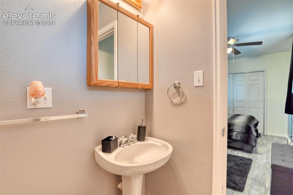 Image 34 of 46: Pedestal sink with chrome faucet, complemented by a wood-framed medicine ca