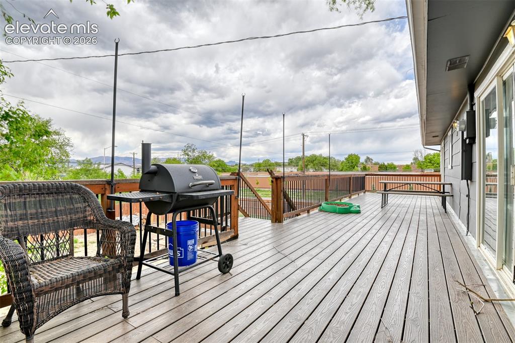 Image 37 of 46: Spacious outdoor deck featuring gray wood-finish flooring, a dark wood rail
