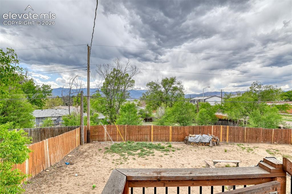 Image 40 of 46: Expansive fenced backyard with sand and natural ground cover