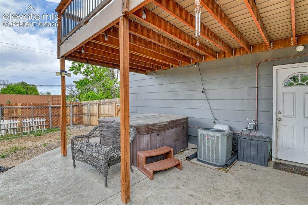 Image 42 of 46: Concrete patio beneath a wooden deck featuring a built-in spa, exterior sid