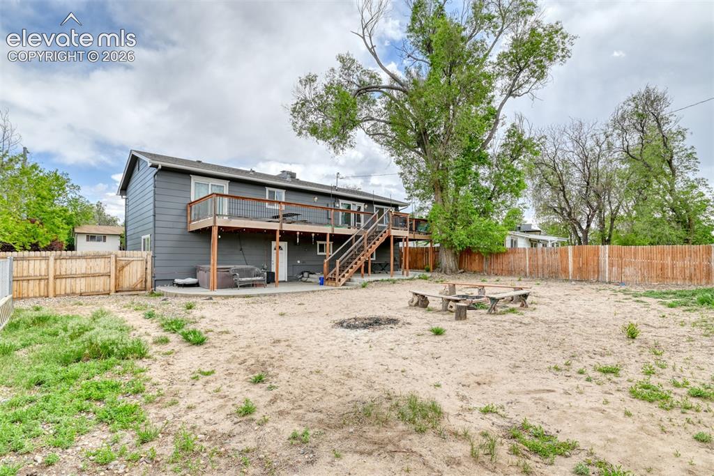 Image 43 of 46: Expansive backyard featuring a fire pit with log seating, a wood privacy fe