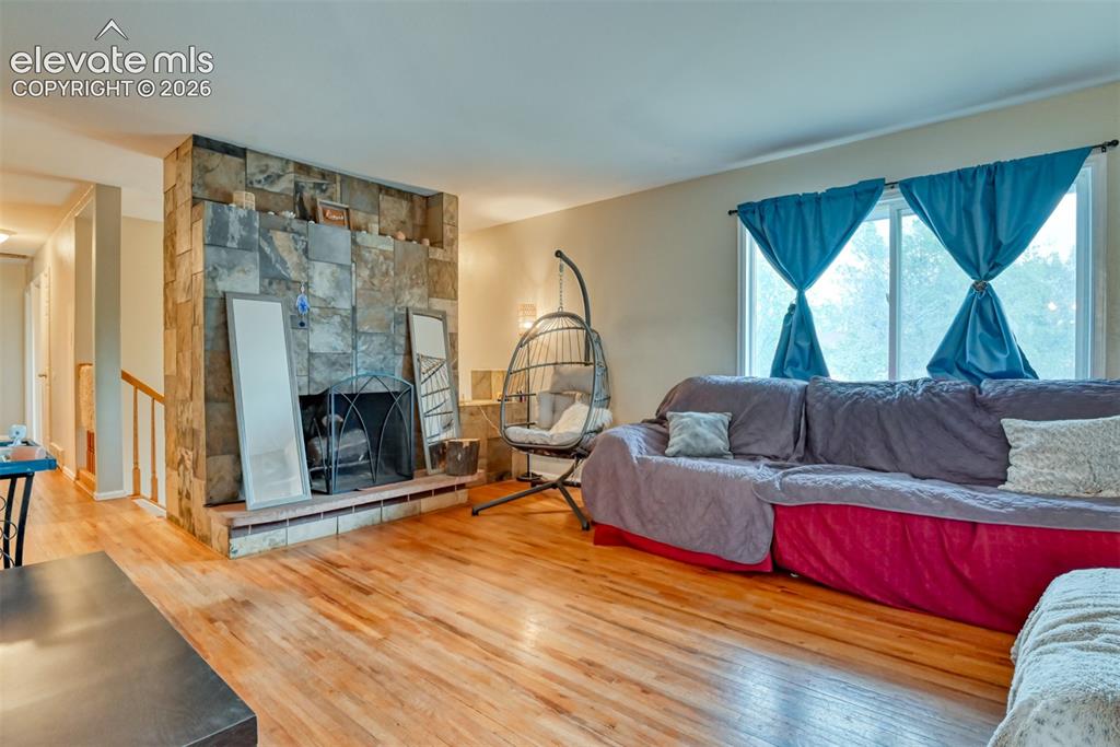 Image 6 of 46: Living area featuring wood-finish flooring, a stone-clad fireplace with a h