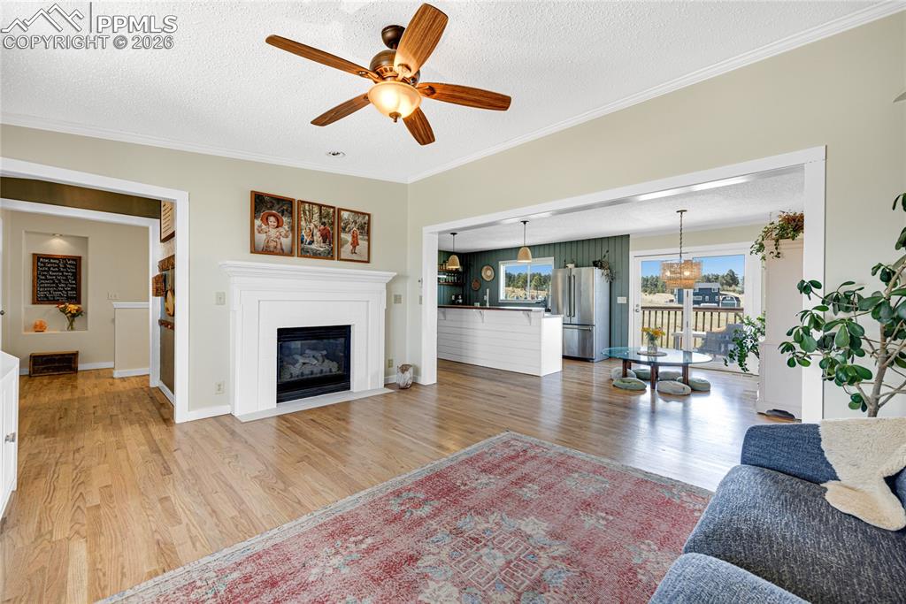 Image 11 of 42: Living area featuring hardwood floors, a white fireplace with a mantel, and
