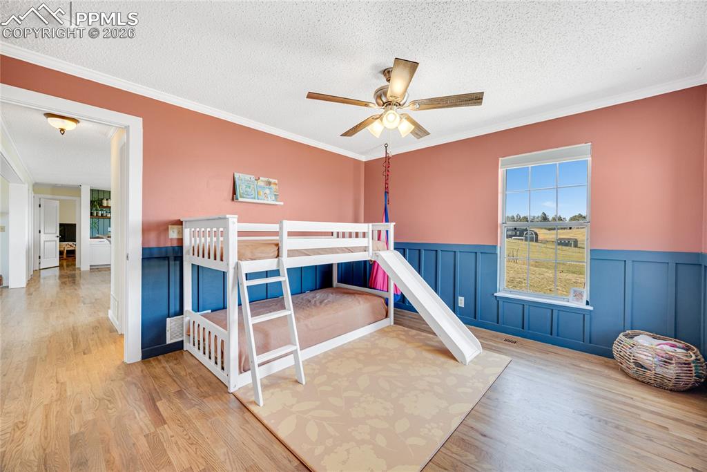 Image 17 of 42: This interior space features hardwood flooring, custom wainscoting, a ceili