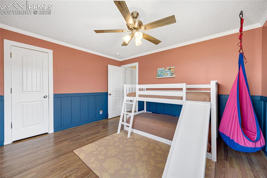 Image 18 of 42: This room features hardwood flooring, white crown molding, custom wainscoti