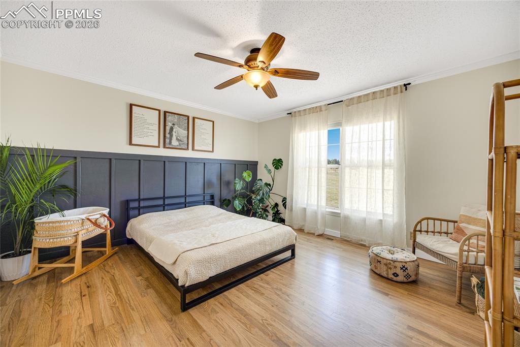 Image 21 of 42: This bedroom features hardwood floors, a prominent paneled accent wall, and