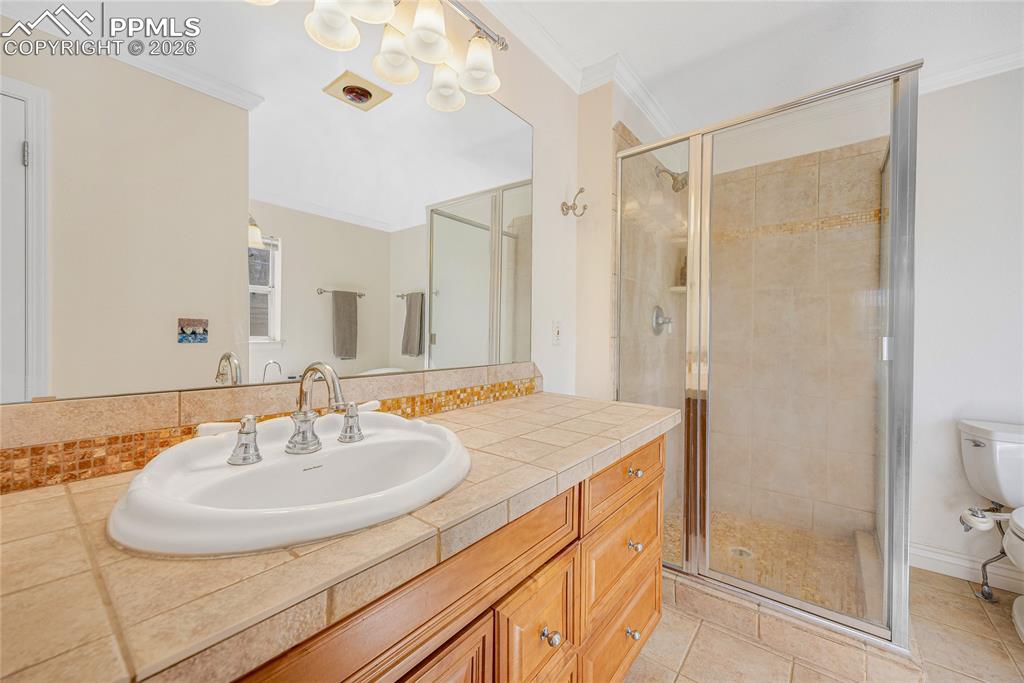 Image 23 of 42: The bathroom features a tiled vanity with a white sink and chrome faucet, a