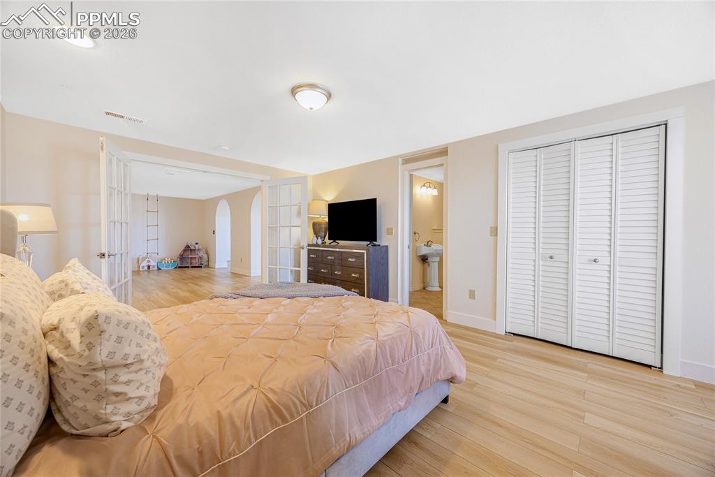 Image 30 of 42: The room features light-colored walls, light wood flooring, and white bi-fo
