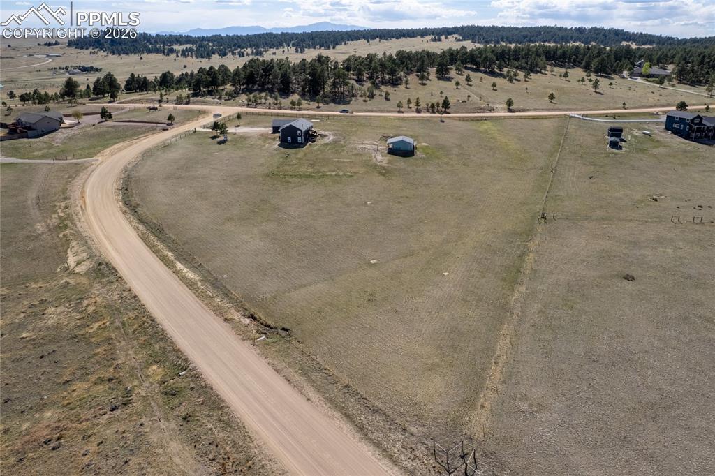 Image 37 of 42: Expansive open land with a curved road and distant tree-lined hills