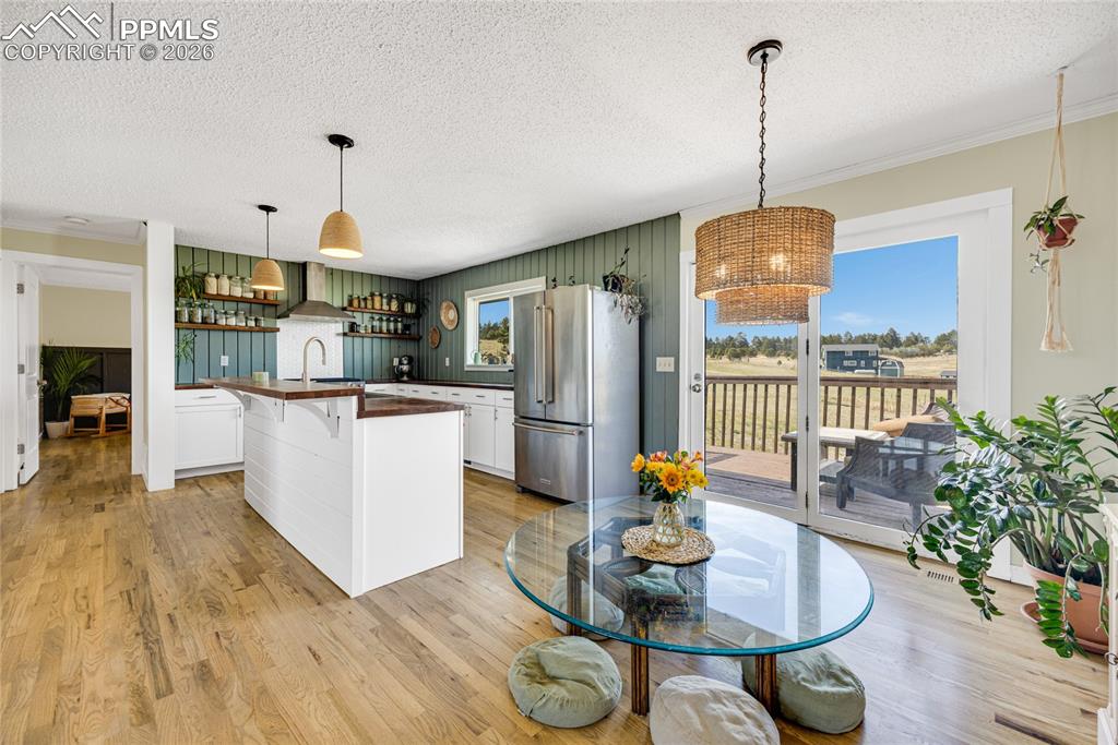 Image 5 of 42: The kitchen and dining area features hardwood floors, white cabinetry, and 