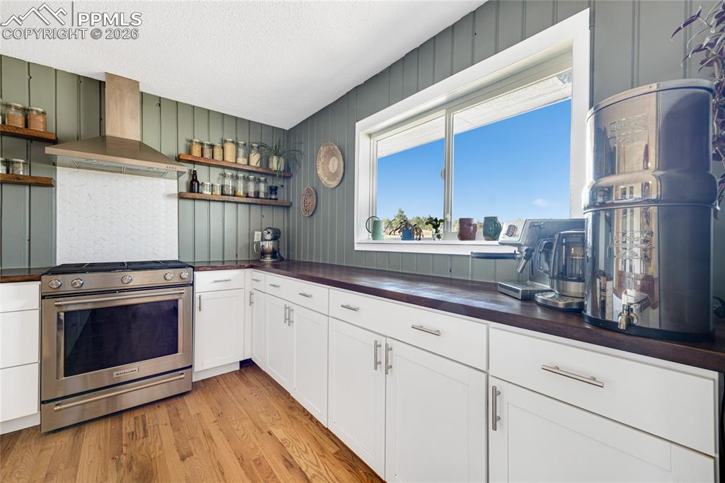 Image 7 of 42: The kitchen features hardwood floors, white cabinetry with silver hardware,