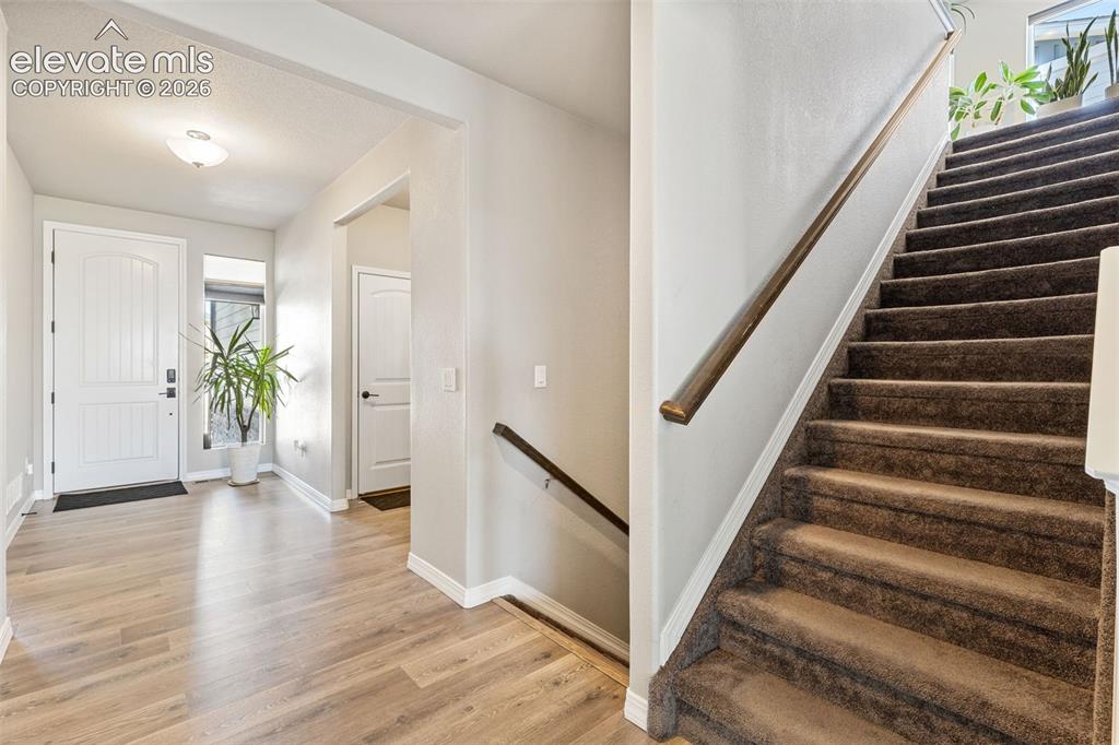 Image 13 of 44: Entryway featuring wood-finish flooring, a white paneled front door with si
