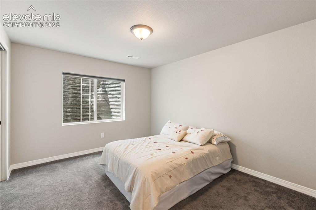 Image 40 of 44: Carpeted room featuring light-toned walls and a window with a security bar