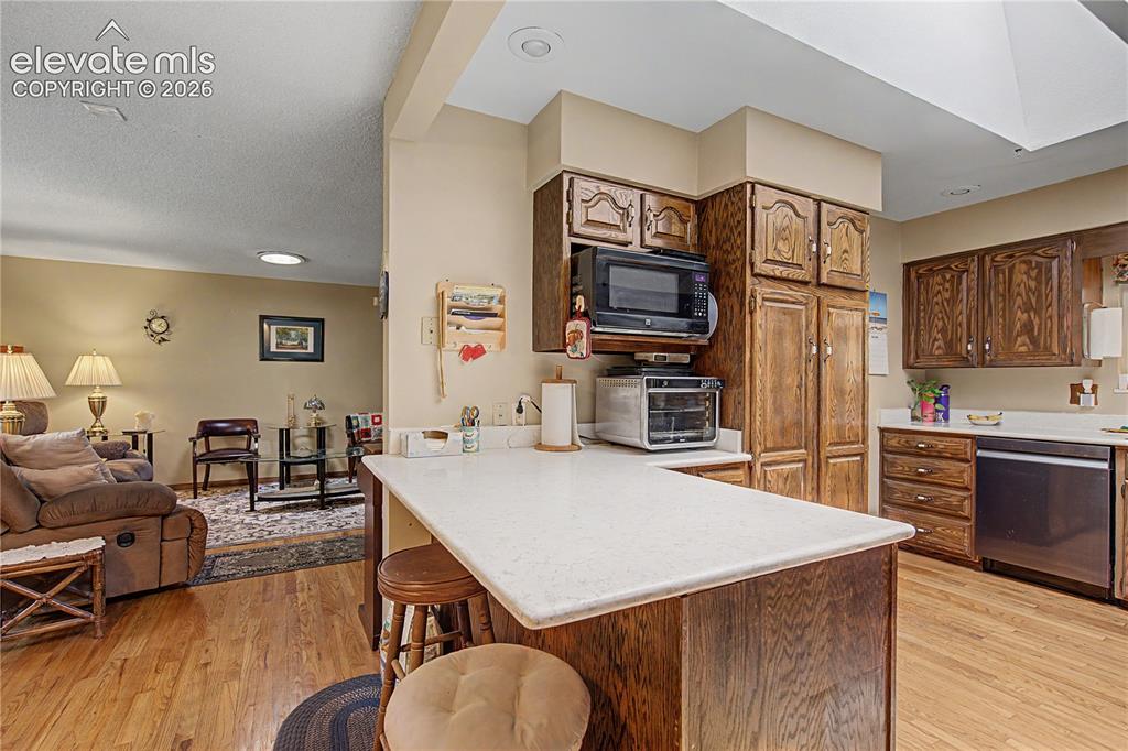 Image 11 of 38: Kitchen with wood-finish flooring, custom cabinetry, and light-toned counte