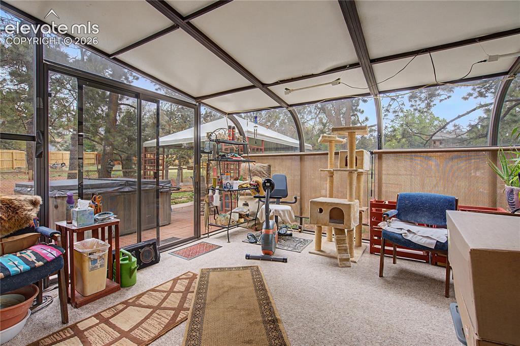 Image 16 of 38: Screened patio featuring a hot tub, outdoor deck, and a partially enclosed