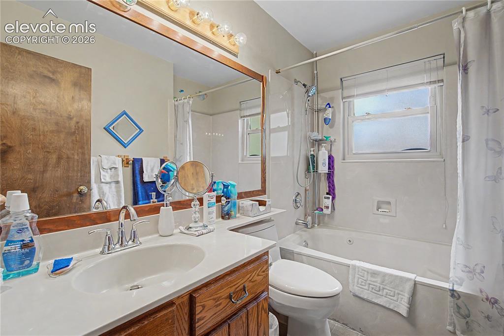 Image 21 of 38: Bathroom featuring a wood-finish vanity with a single basin sink and chrome