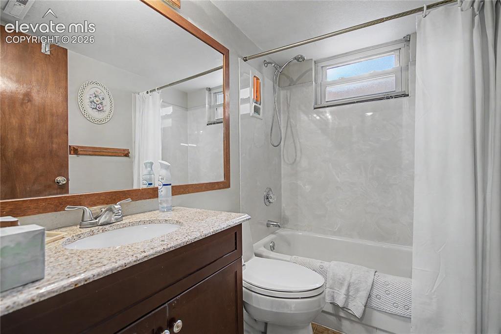 Image 28 of 38: Bathroom featuring a dark wood-finish vanity with a light speckled countert