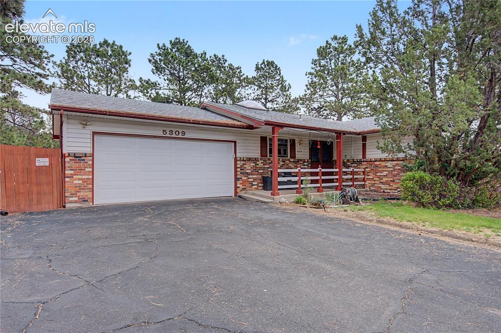 Image 3 of 38: Ranch-style exterior featuring a wide driveway, attached garage, brick and