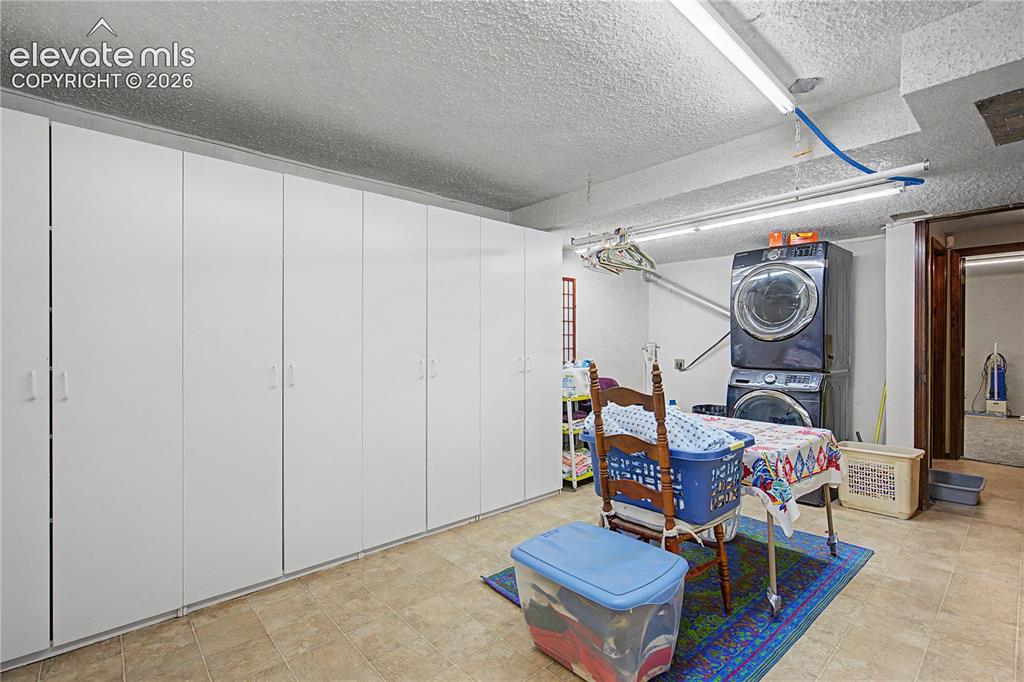 Image 32 of 38: Utility room featuring extensive built-in white cabinetry, stacked washer a