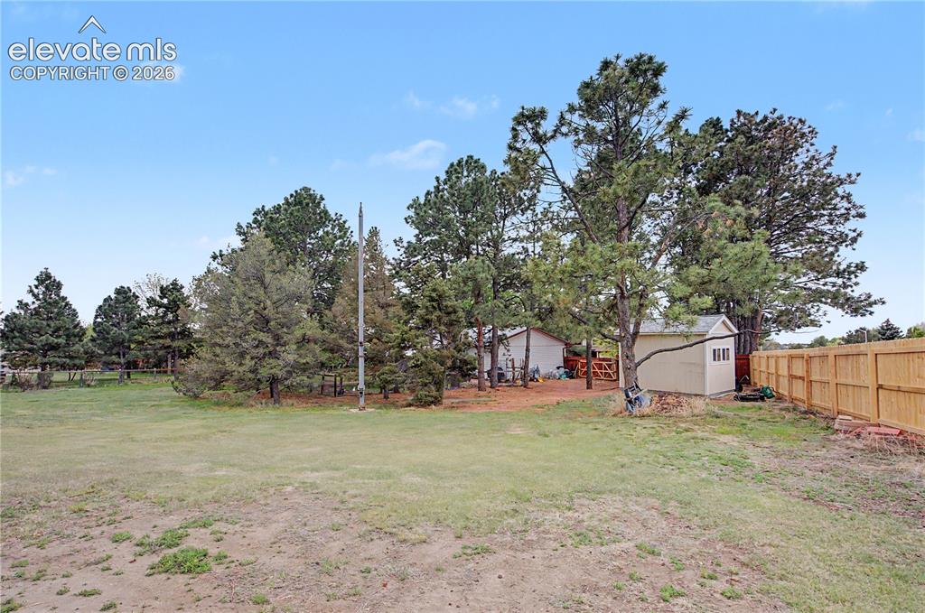 Image 35 of 38: Expansive outdoor space featuring a large lawn area, mature trees, a wooden