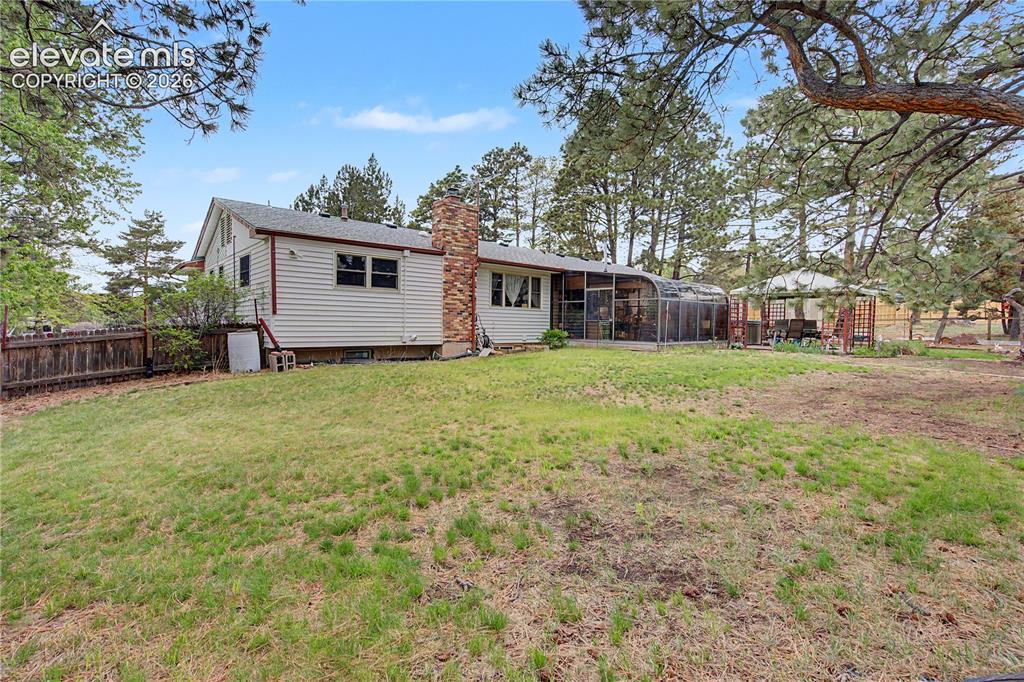 Image 38 of 38: Expansive backyard featuring a gently sloped lawn, mature trees, a screened