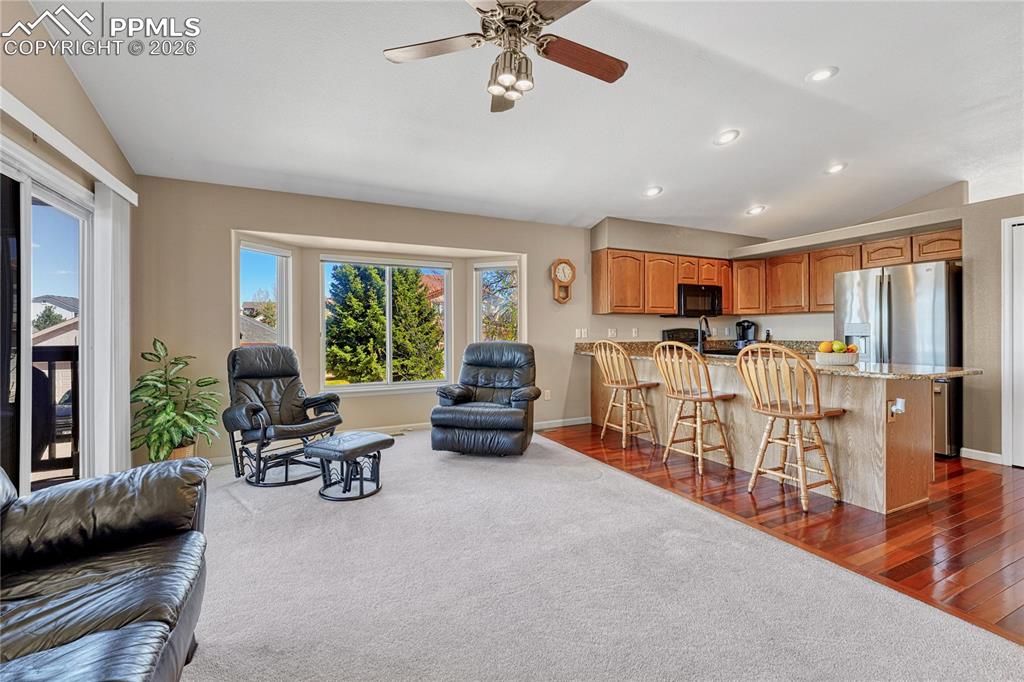 Image 11 of 50: Great room with vaulted ceiling, ceiling fan...