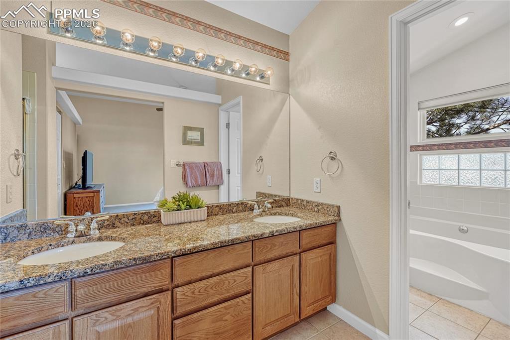Image 21 of 50: Primary bathroom with granite countertops...
