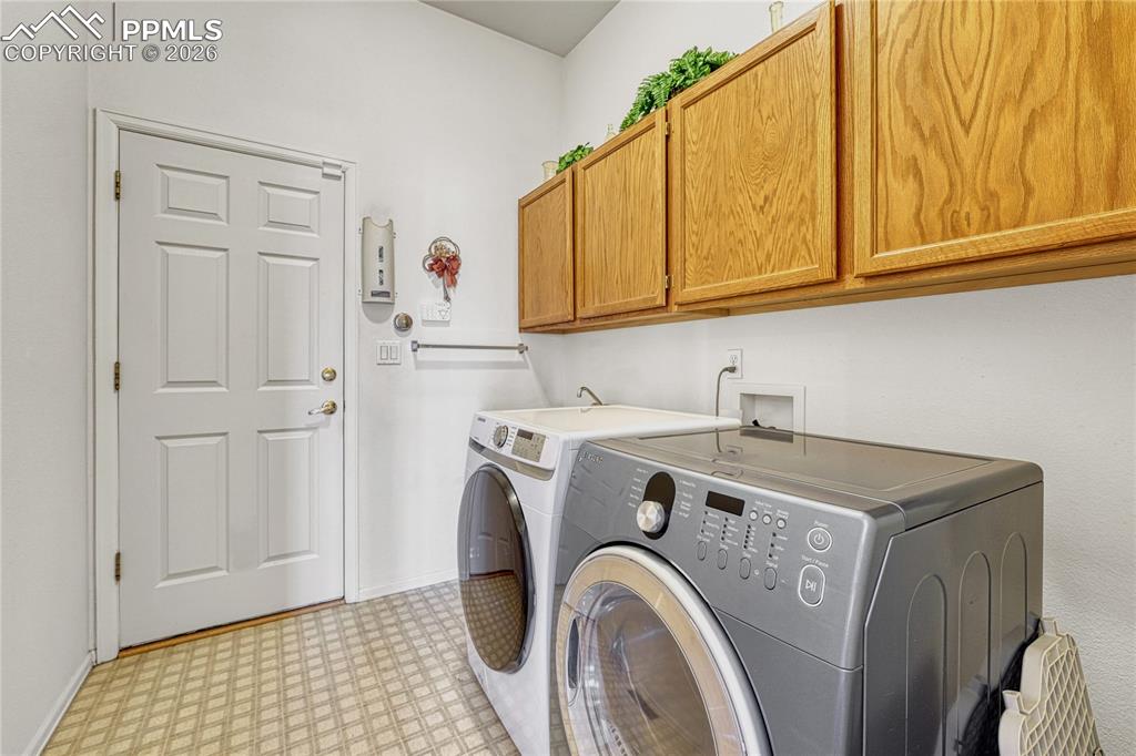 Image 28 of 50: Main level laundry with cabinetry, sink and garage access. 
