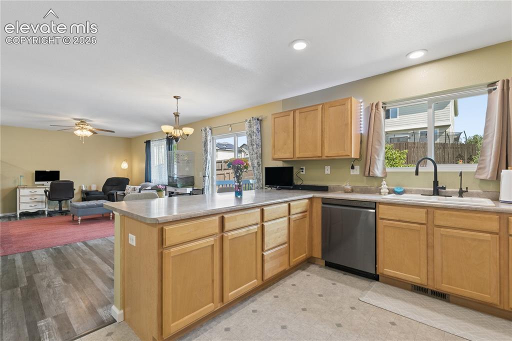 Image 10 of 35: Open-concept kitchen with light wood cabinetry, a stainless steel dishwashe