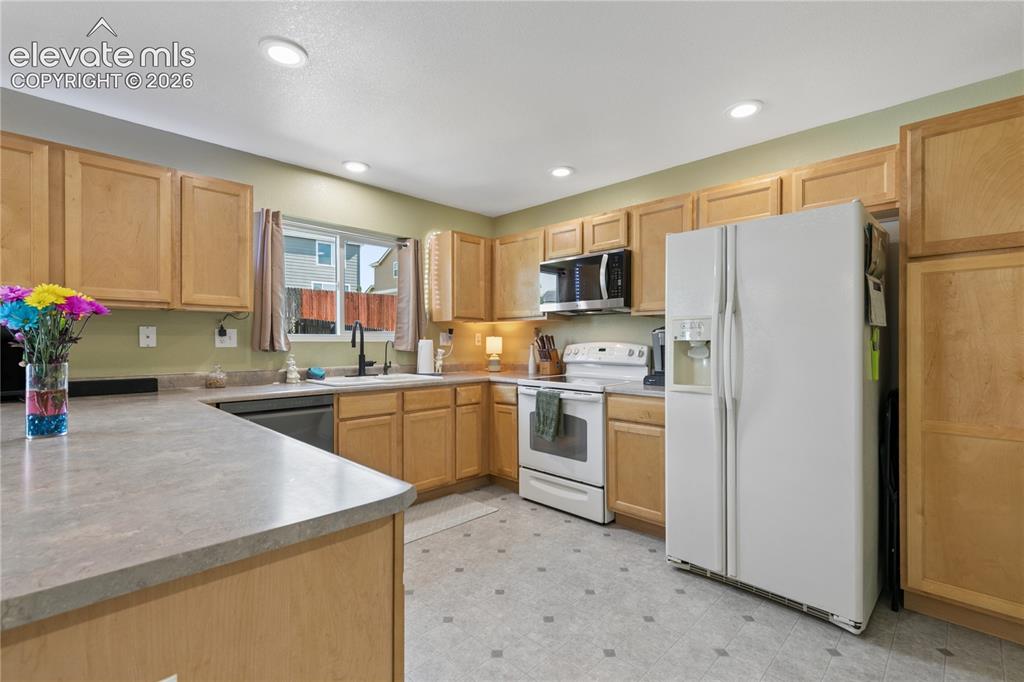 Image 11 of 35: U-shaped kitchen featuring light wood cabinetry, recessed lighting, and a w