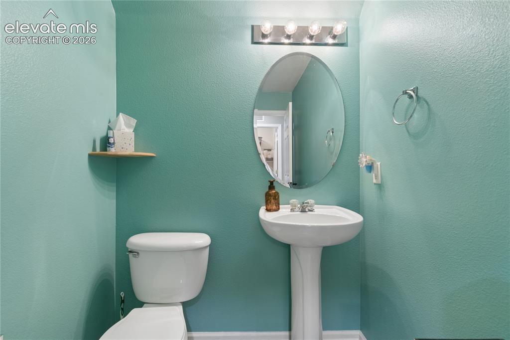 Image 13 of 35: Pedestal sink with an oval mirror, above a toilet with a wall-mounted float