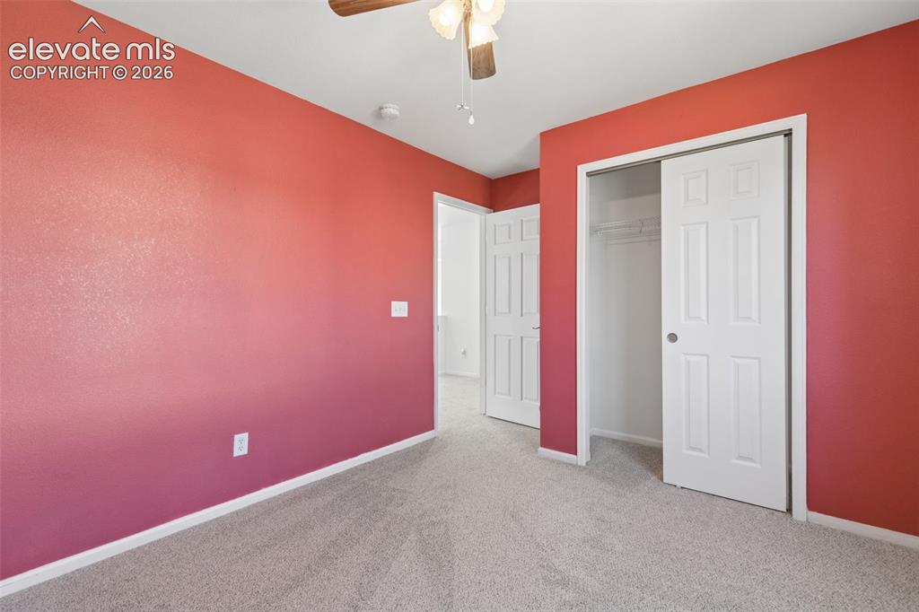Image 17 of 35: Plush carpet flooring, ceiling fan with light fixture, and sliding closet d