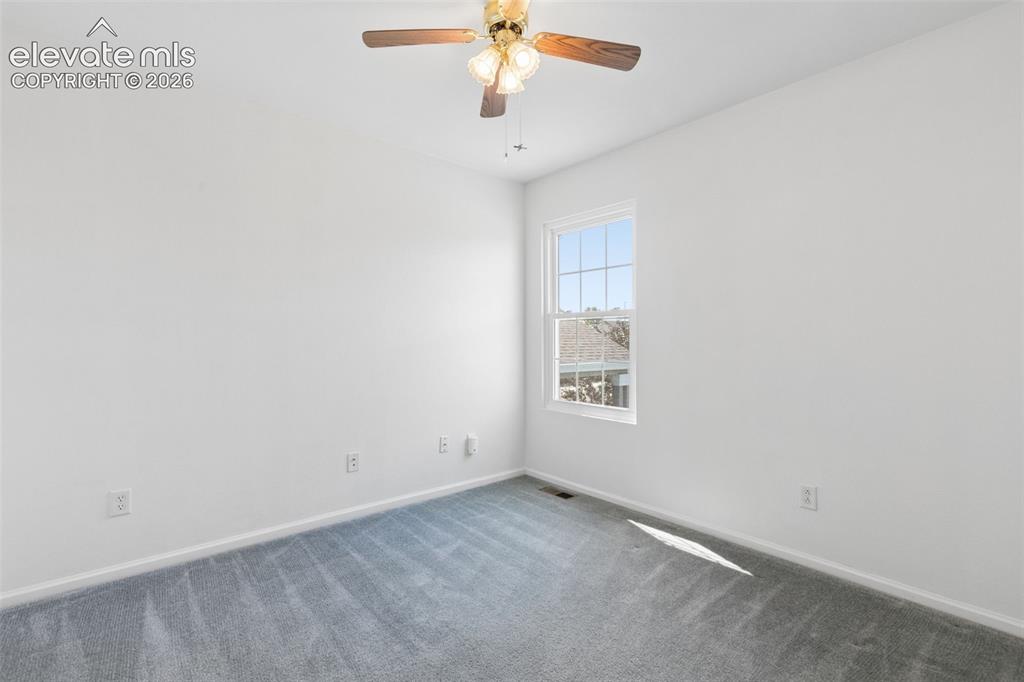 Image 22 of 35: Bright room with white painted walls, gray carpet, and a ceiling fan