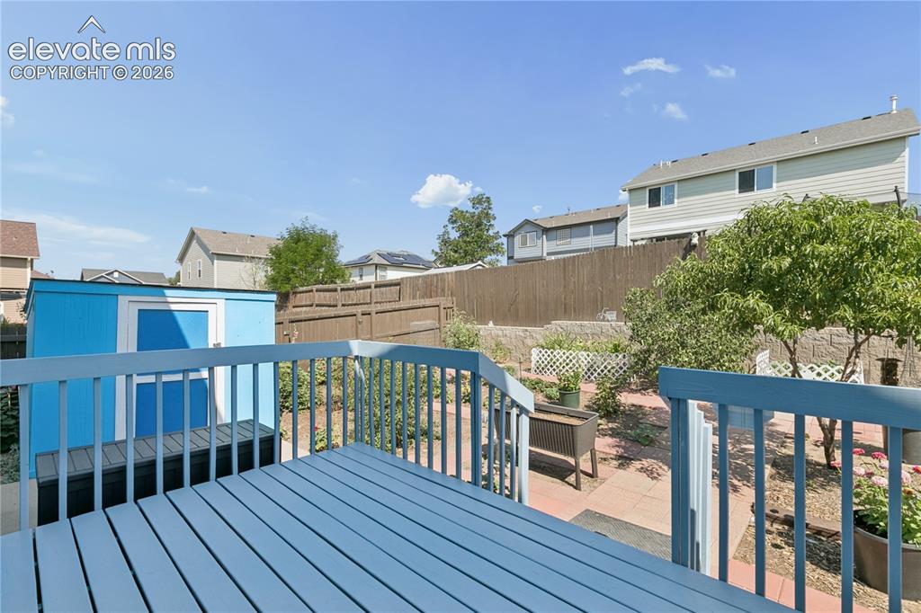 Image 26 of 35: Spacious wooden deck with blue paint, leading to a backyard featuring a blu