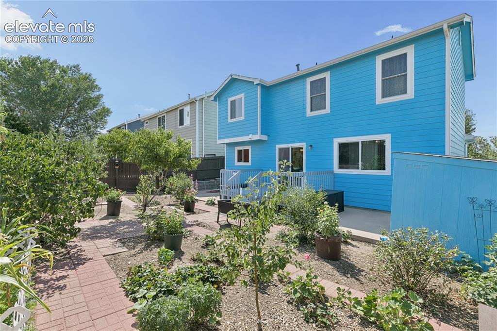 Image 28 of 35: Expansive yard featuring a brick paver pathway, established garden beds, an