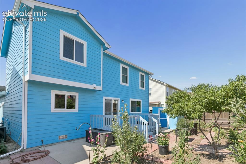 Image 29 of 35: Exterior with vibrant blue siding, white trim, and a multi-level deck