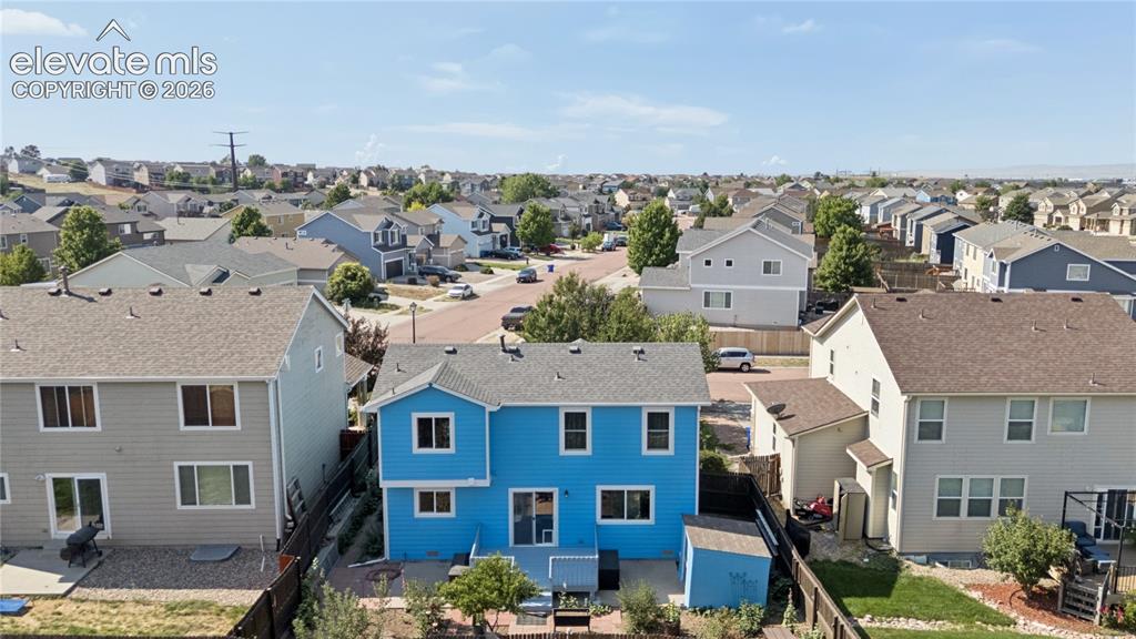 Image 33 of 35: Blue two-story residence with a patio, fenced yard, and an exterior shed