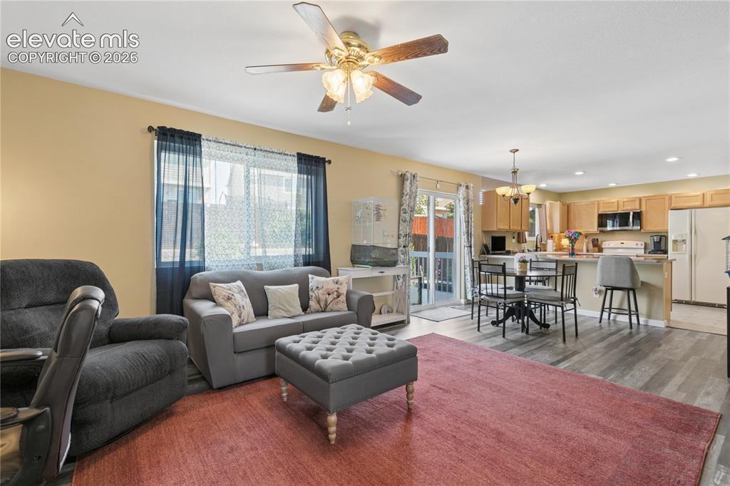 Image 5 of 35: Open-concept living space with wood-finish flooring, a ceiling fan, and sli