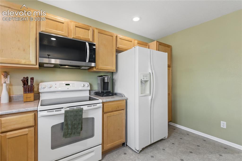Image 9 of 35: Kitchen featuring wood-finish cabinetry, built-in microwave, white electric