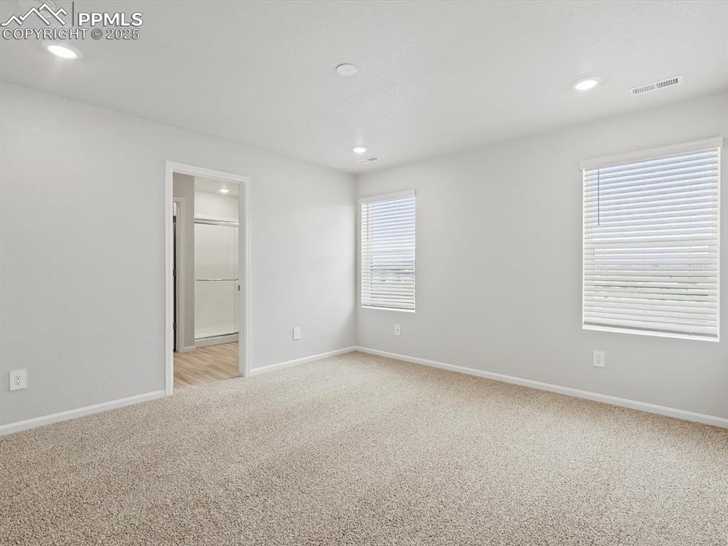 Image 11 of 22: Unfurnished bedroom featuring light carpet, recessed lighting, and ensuite