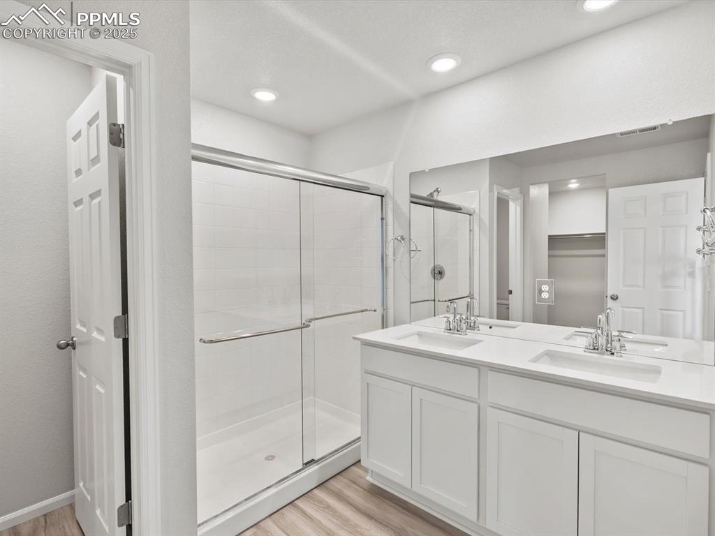 Image 13 of 22: Full bath with a shower stall, wood finished floors, double vanity, and rec