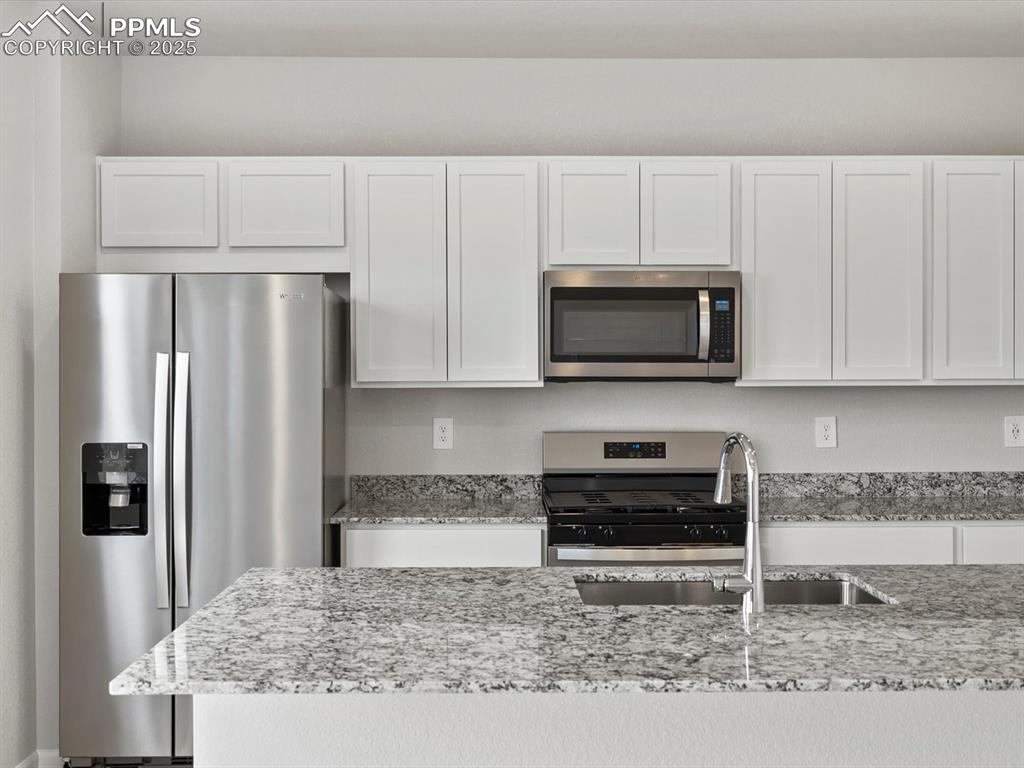 Image 2 of 22: Kitchen featuring stainless steel appliances, white cabinetry, and light st