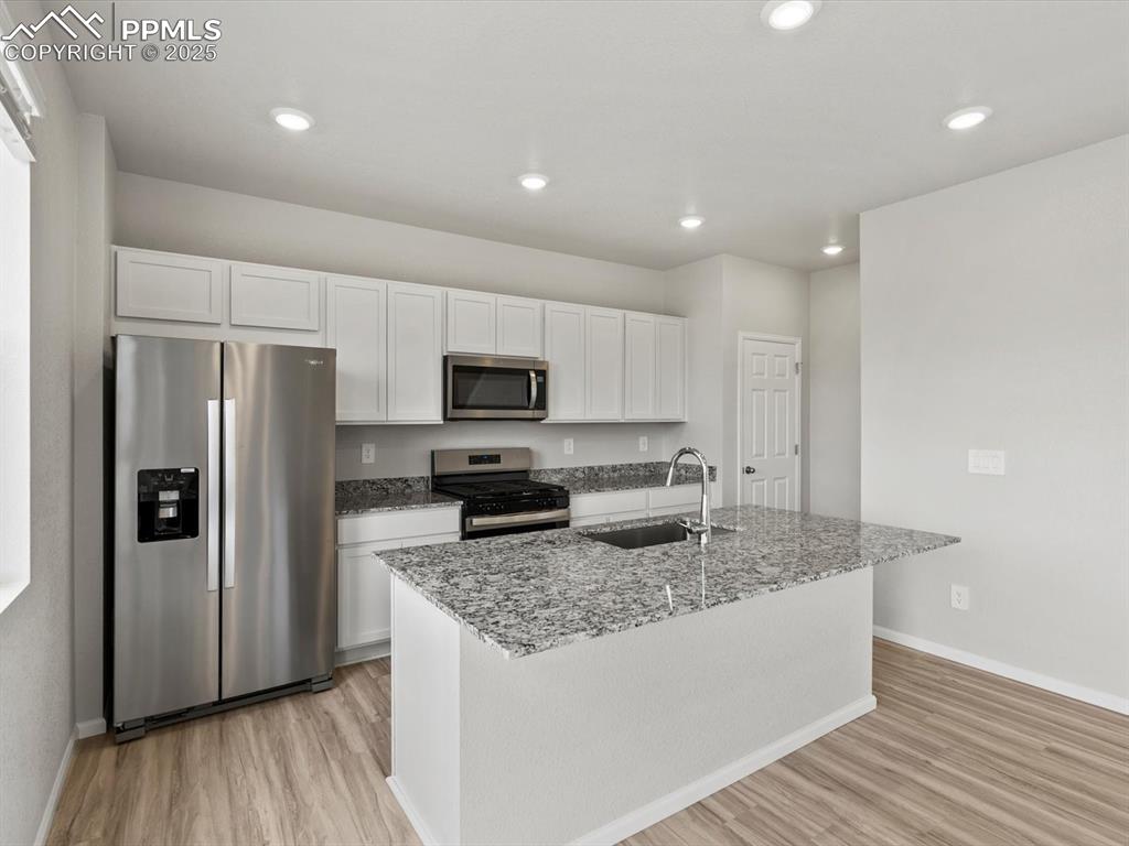 Image 3 of 22: Kitchen with appliances with stainless steel finishes, white cabinets, ligh