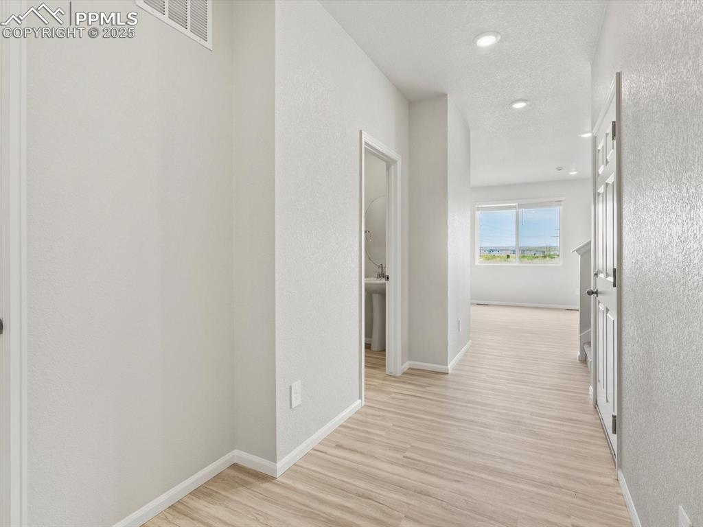 Image 8 of 22: Hallway featuring light wood finished floors, a textured ceiling, and reces