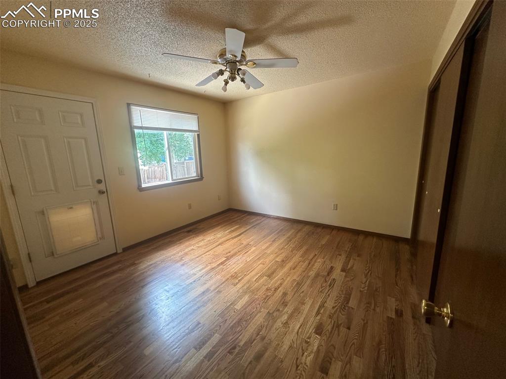 Image 12 of 22: Main bedroom with a textured ceiling, wood finished floors, ceiling fan, an