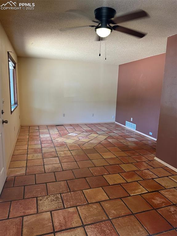 Image 4 of 22: Living room featuring a ceiling fan, a textured ceiling, and mexican tile f